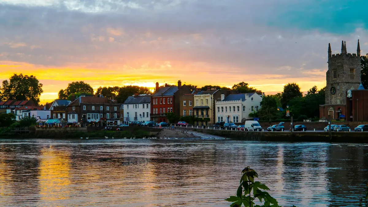 Riverside houses and a church tower across the Thames at sunset near Isleworth in Richmond