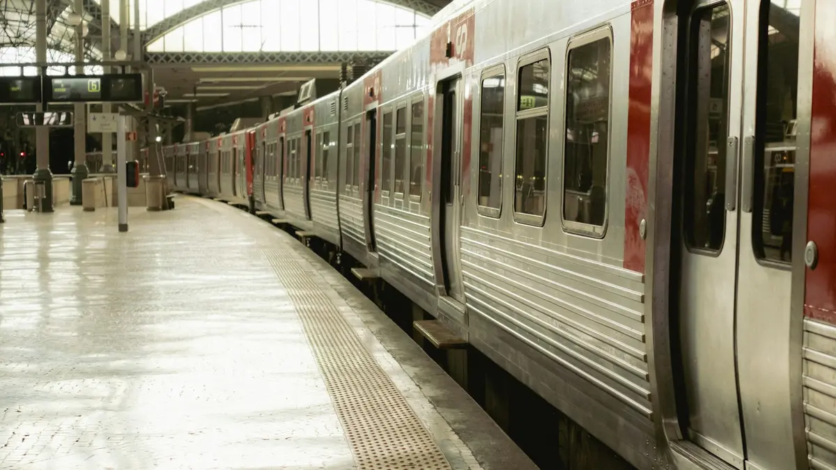 Silver-and-red suburban train beside an empty platform under the arched roof of Rossio Train Station