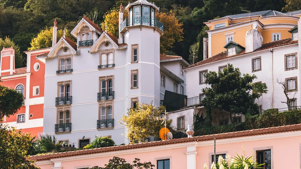 Colorful historic buildings below a wooded hillside in Sintra