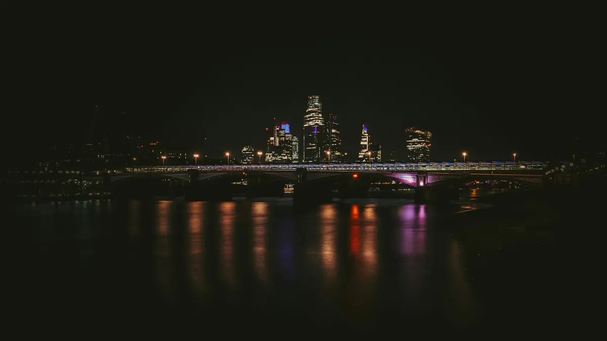 Blackfriars Bridge and the City skyline reflected in the River Thames at night from South Bank