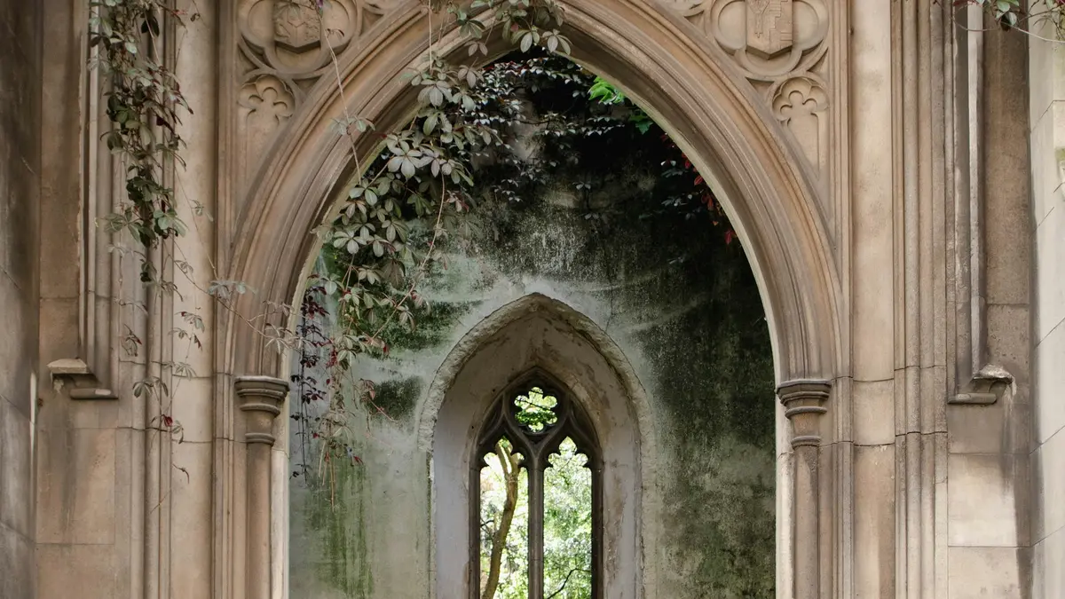Vines growing around layered Gothic stone arches and an open window at St Dunstan in the East Church Garden