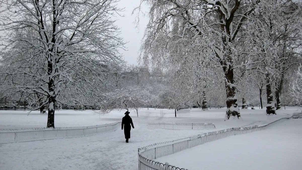 A lone distant pedestrian walking through snow-covered St James's Park in London