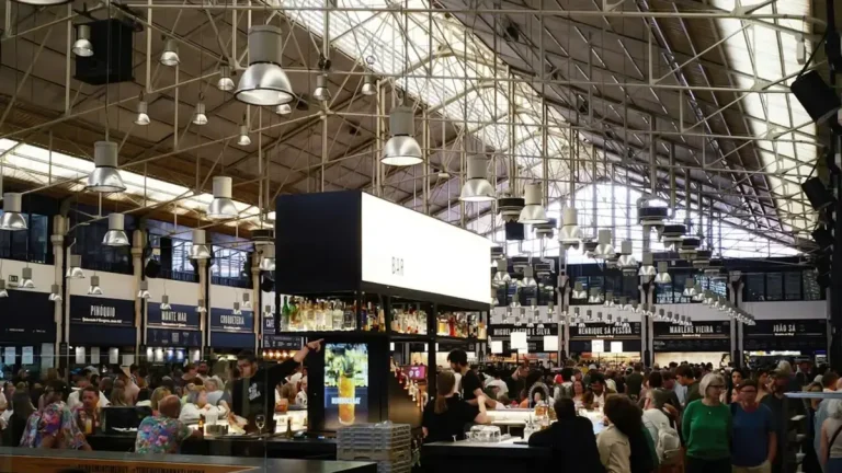 Crowded communal dining hall beneath the iron roof of Time Out Market Lisbon