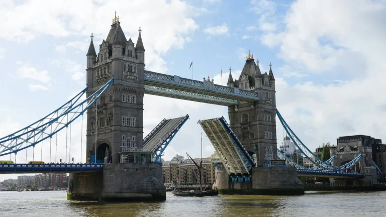 Tower Bridge over the Thames with both bascules raised beneath a partly cloudy sky