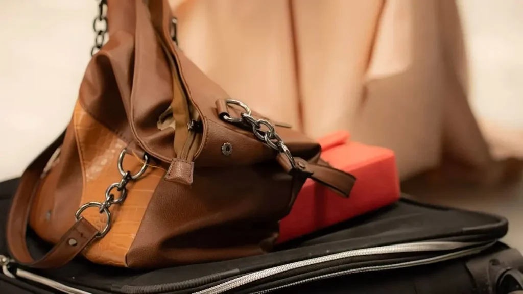 Woman putting on shoes beside packed luggage before a trip