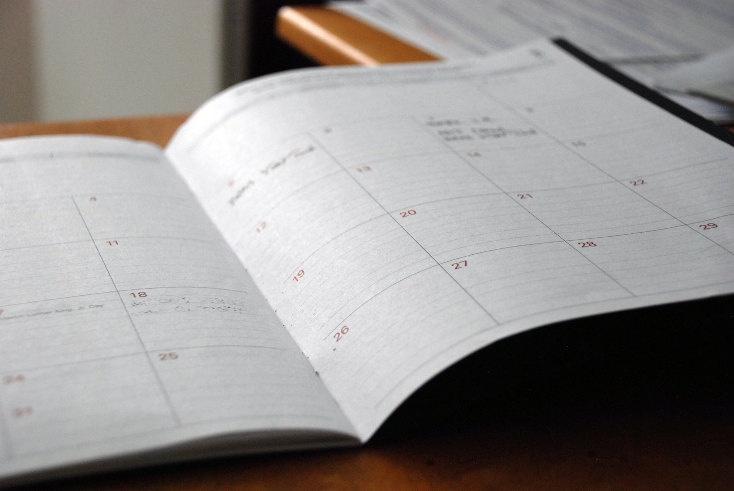 An open monthly planner on a wooden desk