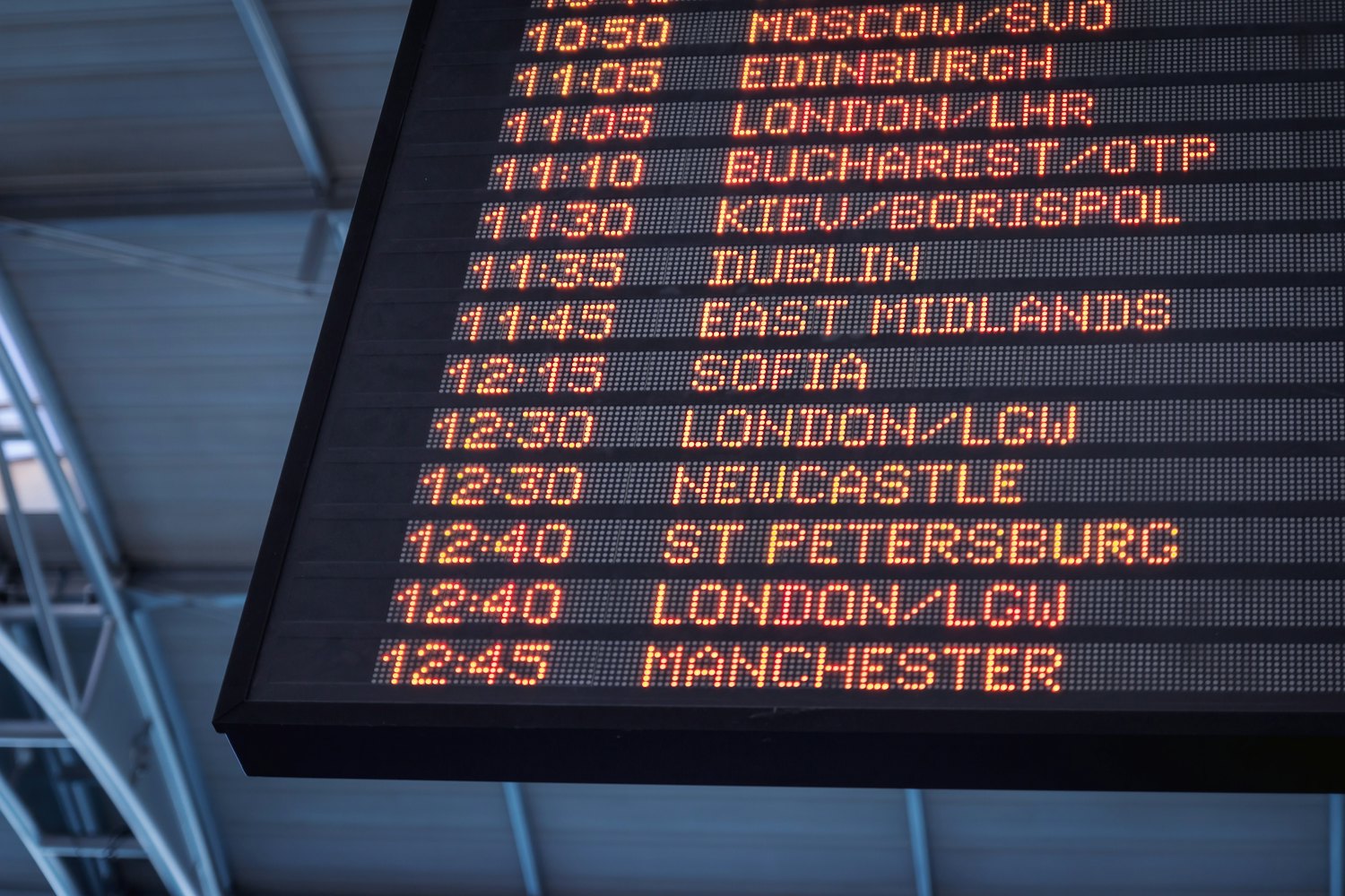 An airport departures board listing European cities