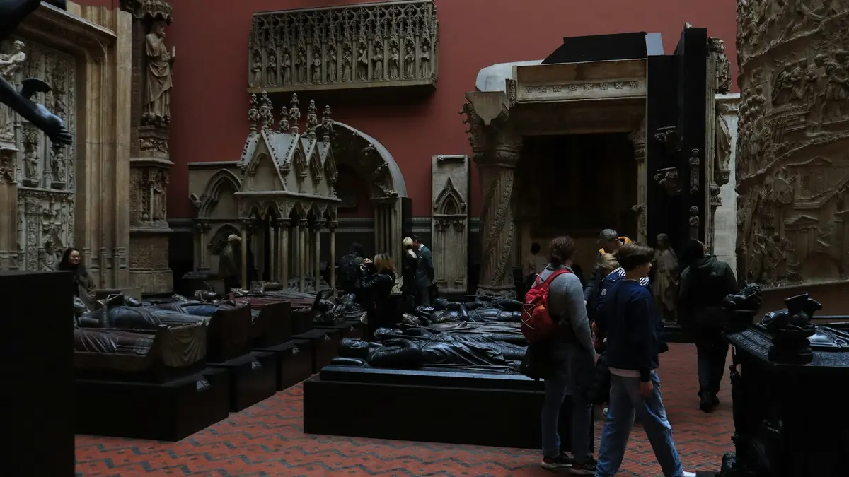 Visitors among large architectural casts in a red-walled gallery at the V&A in South Kensington