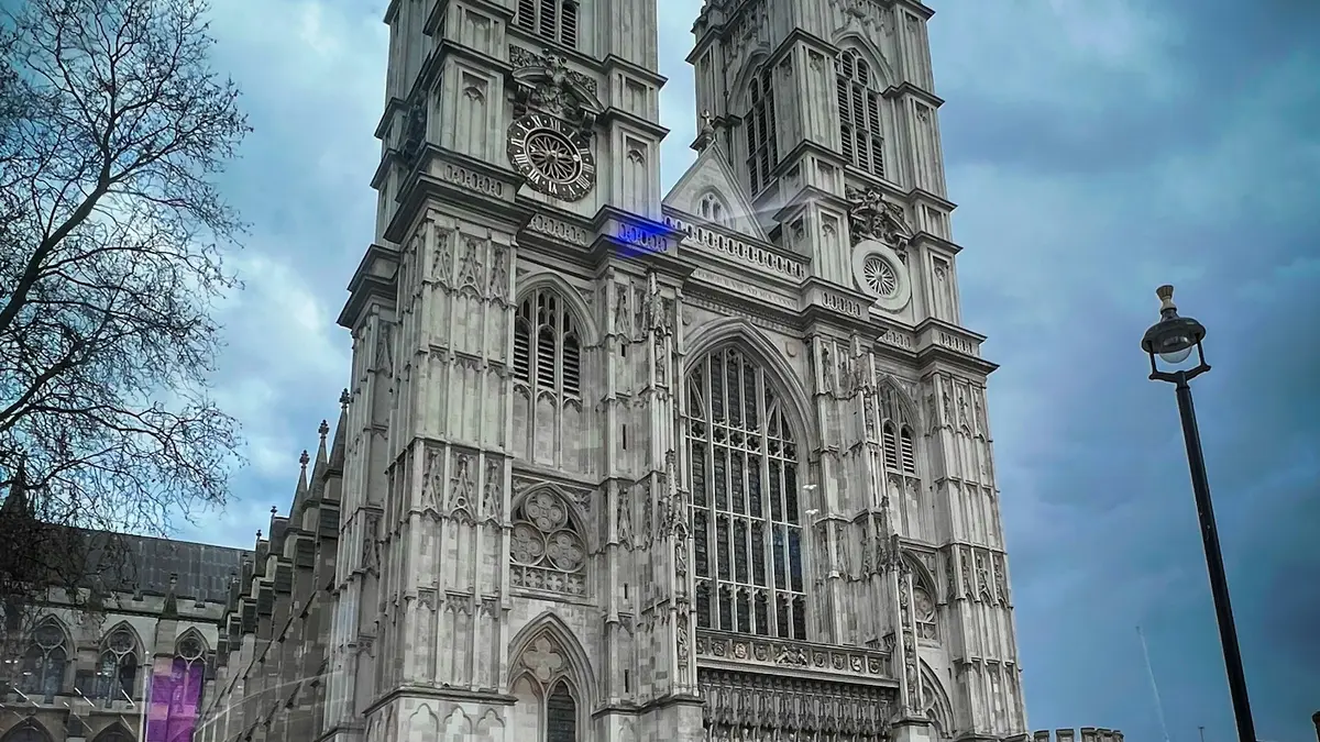 Westminster Abbey's west front and twin towers beneath a blue-gray sky