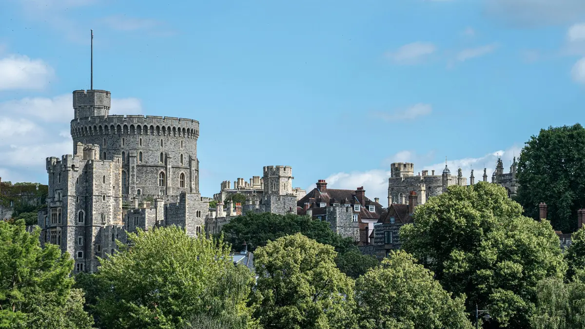 Round Tower and stone buildings of Windsor Castle rising above leafy trees