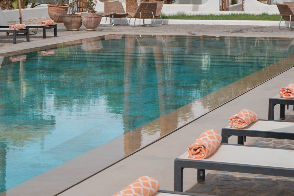 Lounge chairs with folded towels beside a resort pool