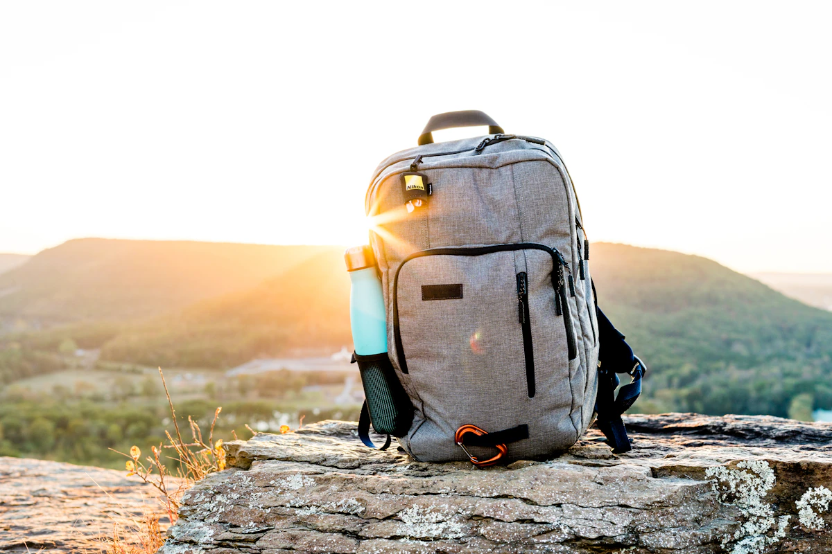 A packed travel backpack resting on a rock at sunset