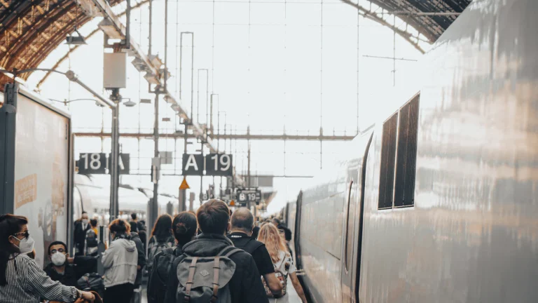 Travelers with backpacks walking toward a train in a European station