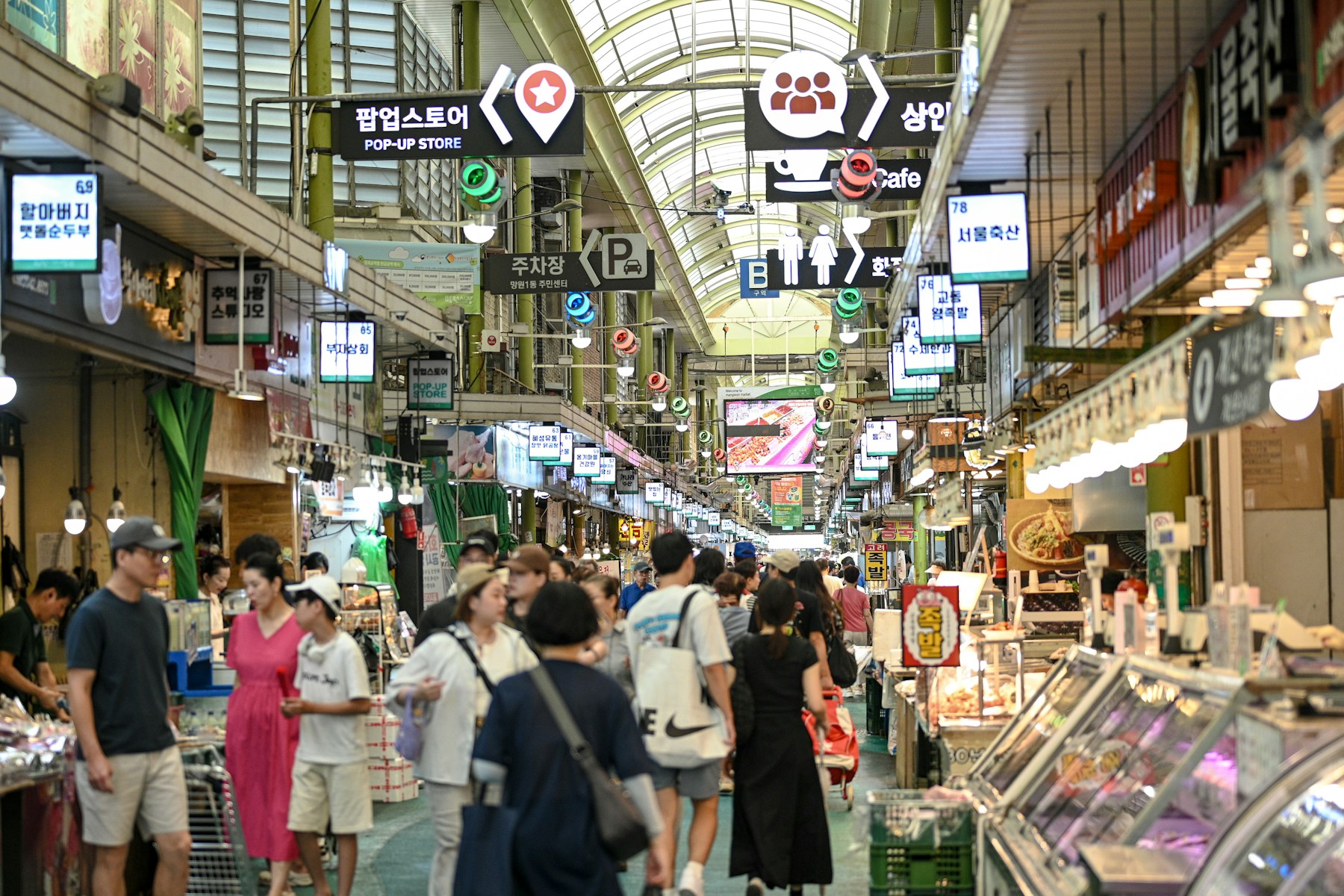 Visitors walking between food stalls inside Mangwon Market in Seoul