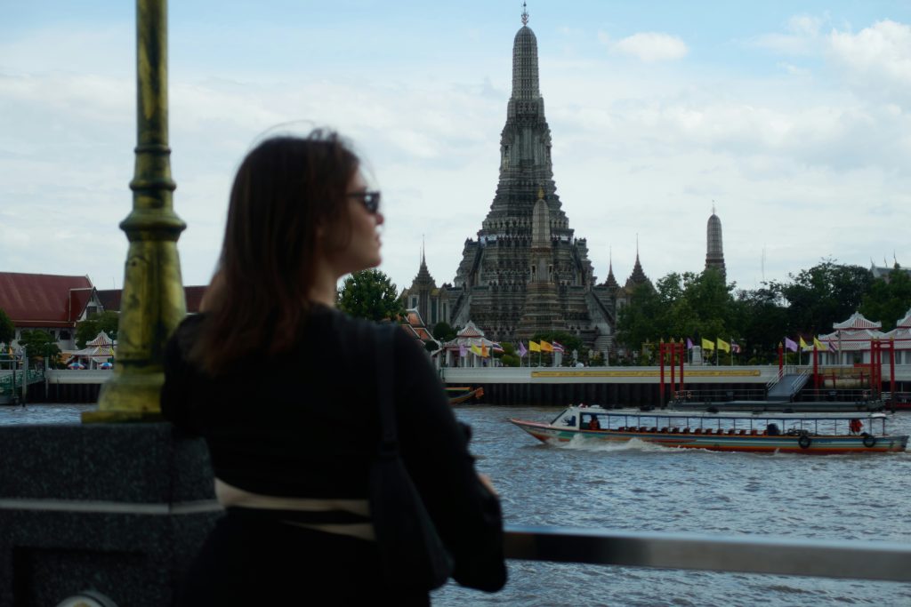 Solo female traveller looking toward Wat Arun temple in Bangkok, Thailand