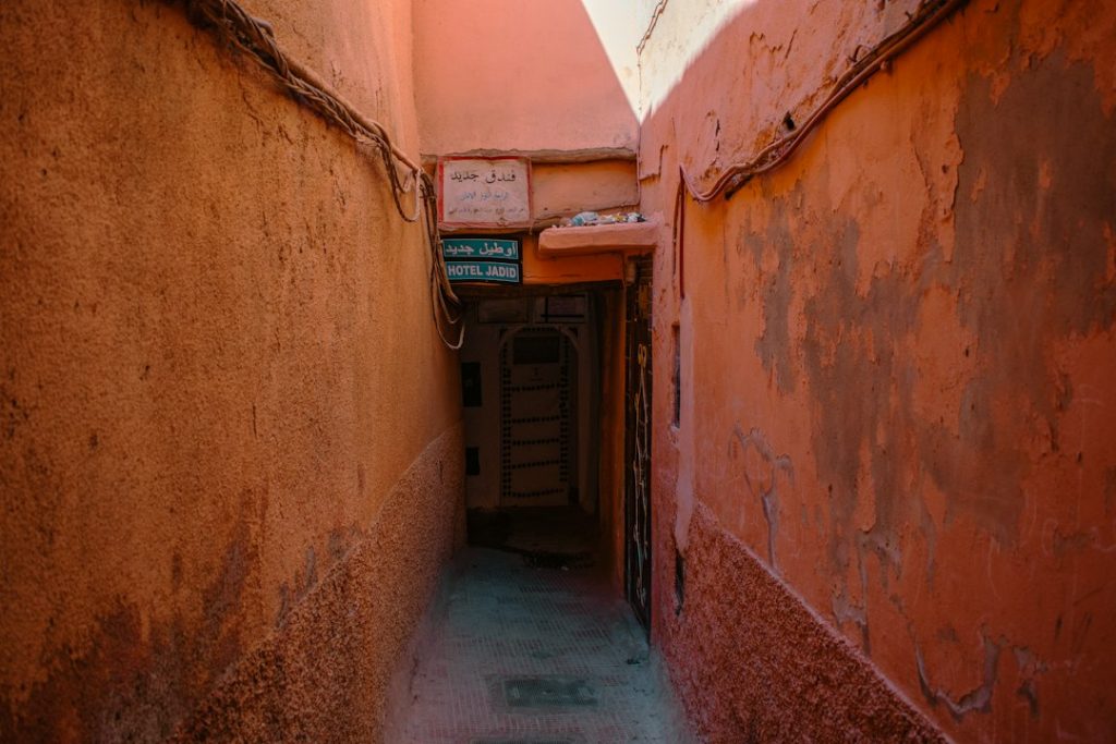 A narrow, orange alleyway leads to a dark door