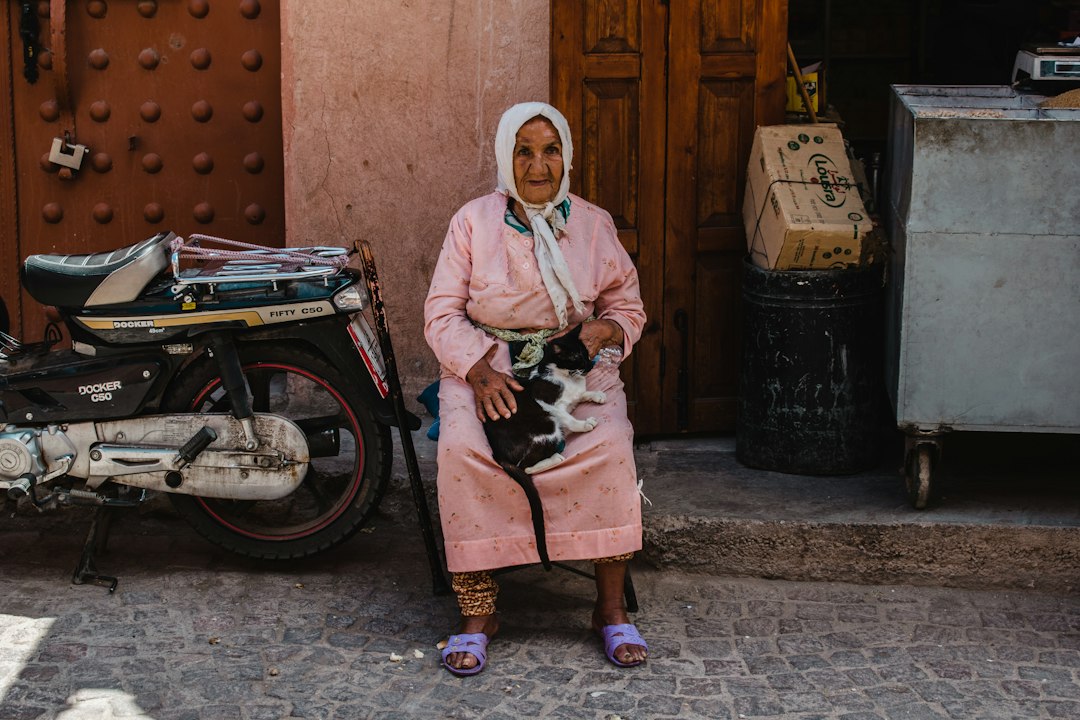 Elderly woman holding a cat in a street